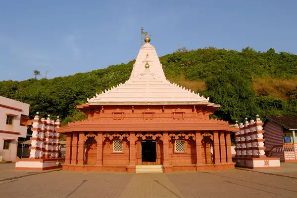 Swayambhu Ganapati tapınağı, arkasında lamba direkleri ve yemyeşil dağ; Ganapatipule; güney Konkan kıyısı; Bölge Ratnagiri; Maharashtra; Hindistan