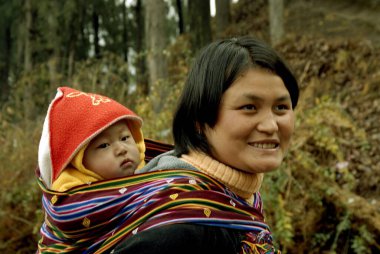 Thimpu 'nun başkenti Bhutan Asya' nın Kraliyet Govt 'unda çocuğunu sırtında taşıyan gülümseyen anne.  
