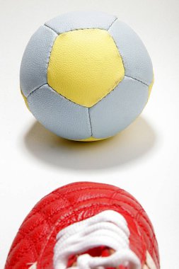 Kırmızı ayakkabı ve sarı ve mavi futbol topu ya da futbol sporu beyaza karşı 