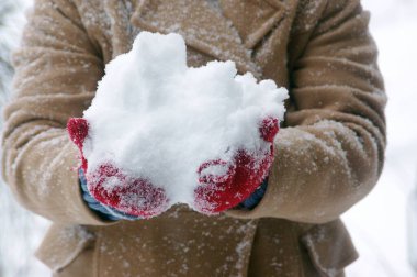 Kar yağarken elinde taze kar olan bir kadın.