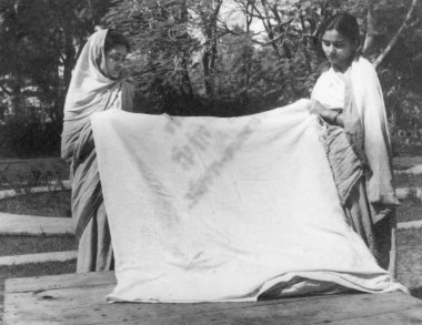 Abha Gandhi and Manu Gandhi, holding the blood stained dhoti dress Mahatma Gandhi wore at his assassination, 1948, India    clipart