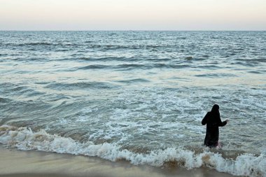 Siyah bir burka giyen Müslüman bir kız Marina Sahili 'nde dalgaların keyfini çıkarırken Chennai; Tamil Nadu; Hindistan