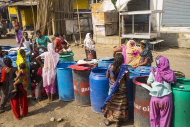 İnsanlar su tankerinden, Bhiwandi 'den, Maharashtra' dan, Hindistan 'dan plastik varillere su dolduruyorlar. 