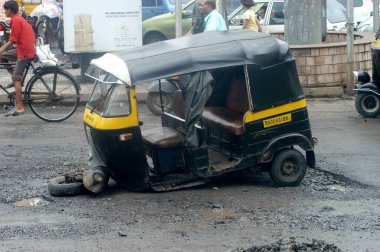 Bombay Mumbai, Maharashtra, Hindistan yakınlarındaki Thane şehrinde trafik sıkışıklığı ve kazalara yol açan ot delikleriyle dolu kötü yol şekli nedeniyle otomobil rickshaw bozuluyor. 