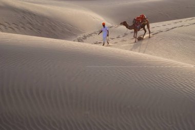 Kum tepeciğini geçen develi adam, Khuri, Jaisalmer, Rajasthan, Hindistan 