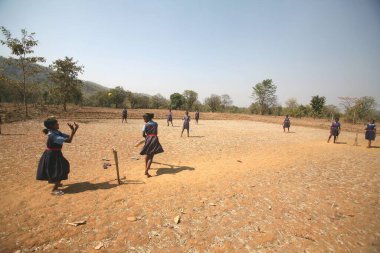 Jharkhand, Hindistan 'daki kuru tarlalarda kriket oynayan üniformalı kızlar. 