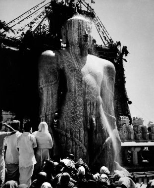 The gigantic statue of jain Gomateshvara Bahubali being bath in milk during the mahamastakabhisheka (the great anointing) festival, Sravanabelahola, Karnataka, India1952  clipart