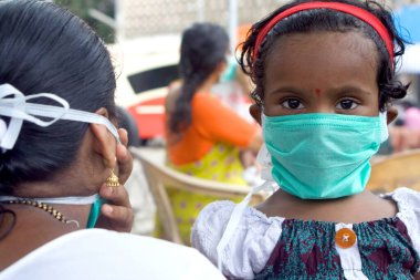 Domuz gribinden, Bombay 'dan, Mumbai' den, Maharashtra 'dan, Hindistan' dan kaçan maskeli anne ve çocuk.   