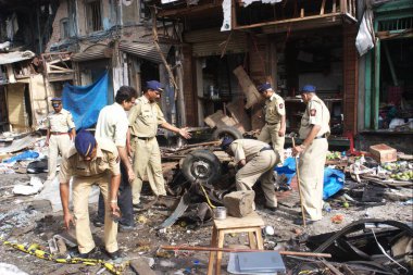 Polisler, Bombay Mumbai, Maharashtra, Hindistan 'daki Zaveri Çarşısı' nda 26 Ağustos 2003 'te meydana gelen güçlü patlayıcılarla hasar gören taksi kalıntılarını inceliyor. 