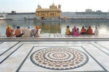 Amrit Sarovar 'ın mermer basamaklarında oturan Sikh nektar gölü, Altın Tapınak; Amritsar, Punjab, Hindistan  