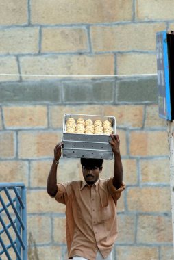 Bir adam, Tirumala, Tirupati, Andhra Pradesh, Hindistan 'daki Venkateshvara tapınağına dağıtmak için kafasında laddoos taşıyor. 