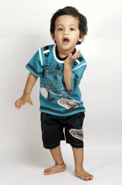 Beyaz arka planda küçük bir Hintli çocuğun tam boy portresi.