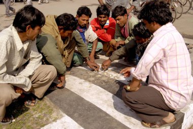 Workers playing sola goti game on road at New Coch Behar railway station ; Calcutta ; West Bengal ; India