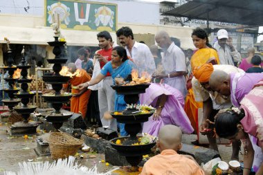 Tirumala Tapınağı, Tirupati, Andhra Pradesh, Hindistan 'daki dev petrol lambalarının önünde Lord Venkateshwara, Balaji' ye tapan ve ona çiçekler sunan dindarlar