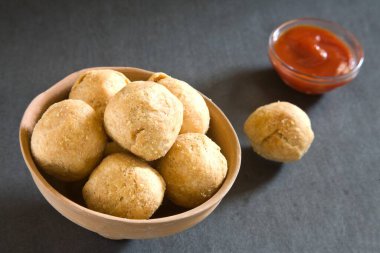 Siyah arka planda domates ketçaplı kachori kızartılmış Hint yemeği.  