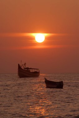 Malpe Sahili, Arap Denizi, Udupi, Karnataka, Hindistan 'da iki taşra balıkçı teknesi ile renkli günbatımı 