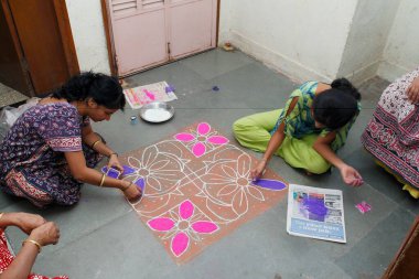 Diwali Deep Awali Festivali, Maharashtra, Hindistan renklerini Rangoli tasarımlarıyla dolduran kadınlar