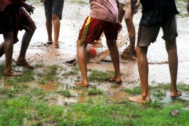 Güney Asyalı Hintli çocuklar muson mevsiminde futbol oynayıp eğleniyorlar.   