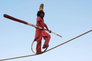 İpte dengede duran bir kız elinde bambu, Pushkar Fair, Rajasthan, Hindistan 