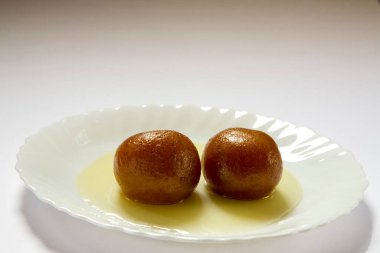 Indian sweet food double pair two piece of round shape Gulabjamun Bonbon Confectionery with sugar syrup served in plate clipart