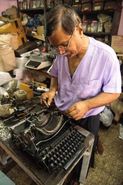 Mumbai, Maharashtra, Hindistan ve Asya 'da eski bir daktiloyu tamir eden teknisyen. 