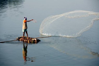 Sangli, Maharashtra, Hindistan 'da Krishna nehrinde balık yakalamak için balıkçı ağlarını attığı derme çatma bir tekneyle Haripur köyünden bir balıkçı.
