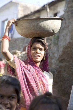 Kafasında taşıyıcı taşıyan kırsal kadın, Bheel basti, Dilwara köyü, Udaipur, Rajasthan, Hindistan 