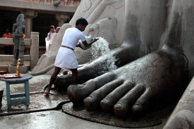 Jain devotee pouring water on foot of saint gomateshwara bahubali, Shravanbelagola, Hassan, Karnataka, India   clipart