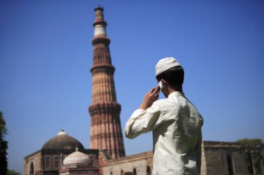 Kutub Minar 'daki cep telefonundan konuşan Müslüman çocuk 1311 kırmızı kumtaşı kulesinde, Hint-Müslüman sanatı, Delhi sultanlığı, Delhi, Hindistan UNESCO Dünya Mirası Sitesi' nde inşa edildi.