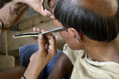 Berber, yürüme yolunda bir insanın saçını kesiyor Kolkata Batı Bengal Hindistan Asya 