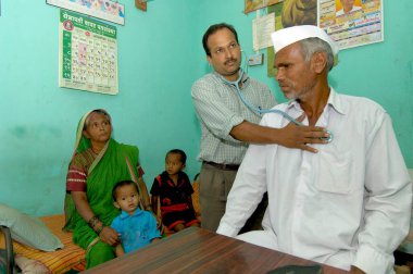 Pune, Maharashtra, Hindistan yakınlarındaki Ralegan Siddhi 'deki özel klinikteki köylüleri muayene eden doktor. 