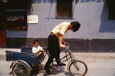 Bir baba çocuğunu Çin 'e, bisiklete binmeye götürür. 