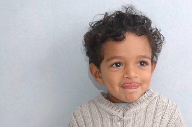 İki buçuk yaşındaki küçük bir çocuk beyaz süveterini giymiş, edepsiz ve gülümseyen bir dille konuşuyor.