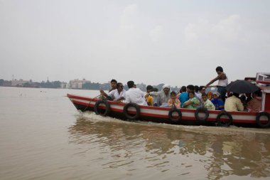 Hooghly Nehri 'ndeki insanlar Dakshineshwar, Kalküta, Kolkata, Batı Bengal, Hindistan' da tekneyle seyahat ediyorlar.  