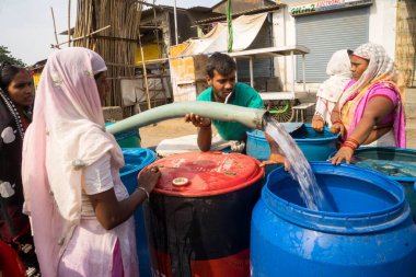 İnsanlar su tankerinden, Bhiwandi 'den, Maharashtra' dan, Hindistan 'dan plastik varillere su dolduruyorlar. 