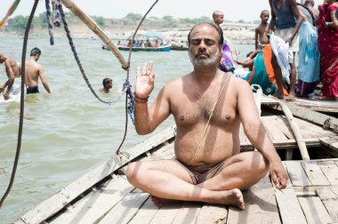 Pilgrims meditation on boat sangam allahabad uttar pradesh  clipart
