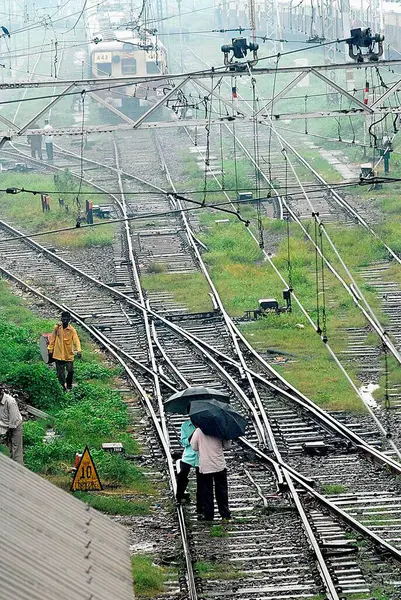 stock image Commuters walk with their umbrellas open on the railway tracks during rains at Kurla Station, Bombay now Mumbai, Maharashtra, India  