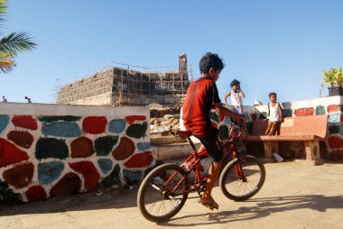Bombay Mumbai, Maharashtra, Hindistan 'daki Worli Kalesi' nin arka planında bisiklet süren genç bir çocuk. 