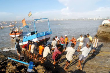 Bombay Mumbai 'deki Worli köyünde, Maharashtra' da, Hindistan 'da muson mevsiminde onarımlar ve bakım için balıkçılar tekneyi kıyıya çeker. 