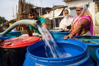 İnsanlar su tankerinden, Bhiwandi 'den, Maharashtra' dan, Hindistan 'dan plastik varillere su dolduruyorlar.