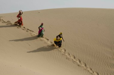 Hindistan 'da Jaisalmer Rajasthan Çölü' nden aşağı koşan sürahiler taşıyan kadınlar.  