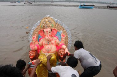 Takipçiler Versova, Bombay Mumbai, Maharashtra, Hindistan 'da büyük Ganesh putunu denize batırıyorlar. 