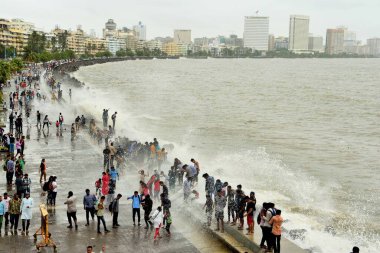 İnsanlar Marine Drive, Mumbai, Maharashtra, Hindistan ve Asya 'da muson deniz dalgalarının tadını çıkarıyorlar.
