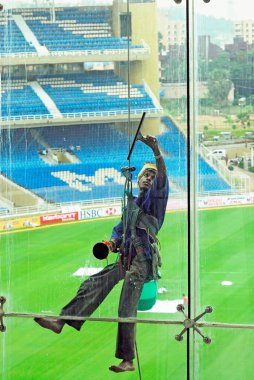 Glass cleaner at D Y Patil cricket stadium, Nerul, Navi Bombay Mumbai, Maharashtra, India    clipart