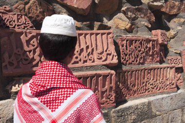 Müslüman çocuk, 1311 yılında inşa edilen kırmızı kumtaşı kulesi, Hint-Müslüman sanatı, Delhi sultanlığı, Delhi, Hindistan UNESCO Dünya Mirası Sitesi 'nde Kur' an 'ın İslami Süslemesini izliyor. 