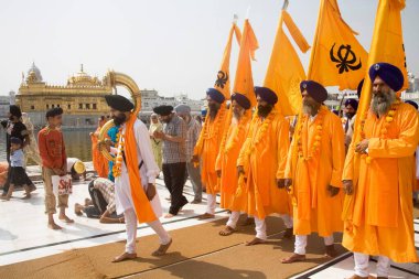 Orange color dressed Sikh men taking out the procession on the occasion of Guru Ramdas Jayanti out side Akal Takht, Swarn Mandir Golden temple, Amritsar, Punjab, India  clipart