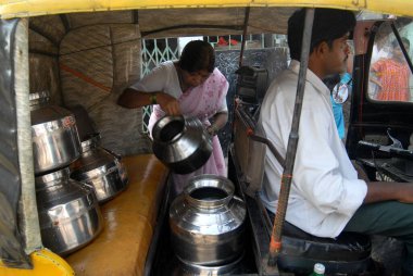 Bir kadın, Chembur, Bombay, Mumbai, Maharashtra, Hindistan 'da bir gecekondu mahallesinde çekçekçekte paslanmaz çelik konteynırlarla su içiyor. 