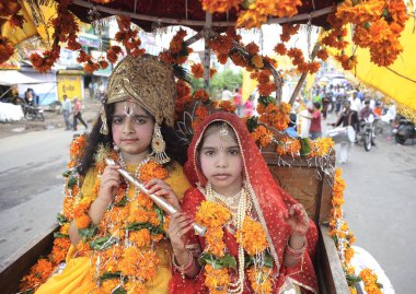 Janmashtami festivali ya da Krishna 'nın doğum günü karnaval alayındaki Krishna ve Radha gibi giyinmiş çocuklar at, Jabalpur, Madhya Pradesh, Hindistan' da oturuyor. 