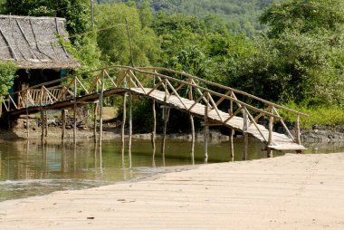 Om sahilindeki bambu köprüsü ile bağlanmış sazdan çatılı kulübeler; Kumta; Karnataka; Hindistan