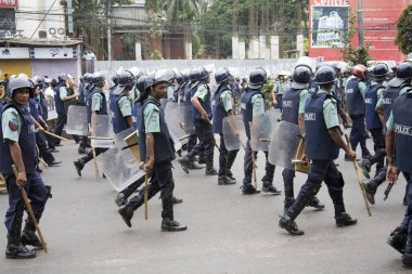 Polis ellerinde sopayla bangladeş 'teki Dhaka eylemini kontrol etmek için yolda yürüyen mavi üniformalı bir polis. 